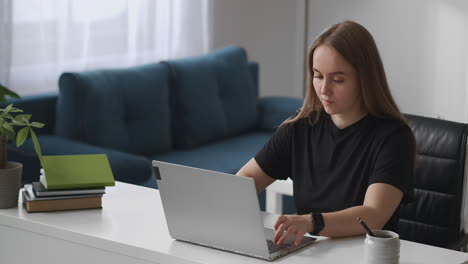 young-woman-seo-specialist-is-working-from-home-typing-on-keyboard-of-modern-laptop-sending-messages-by-internet-medium-portrait-in-living-room